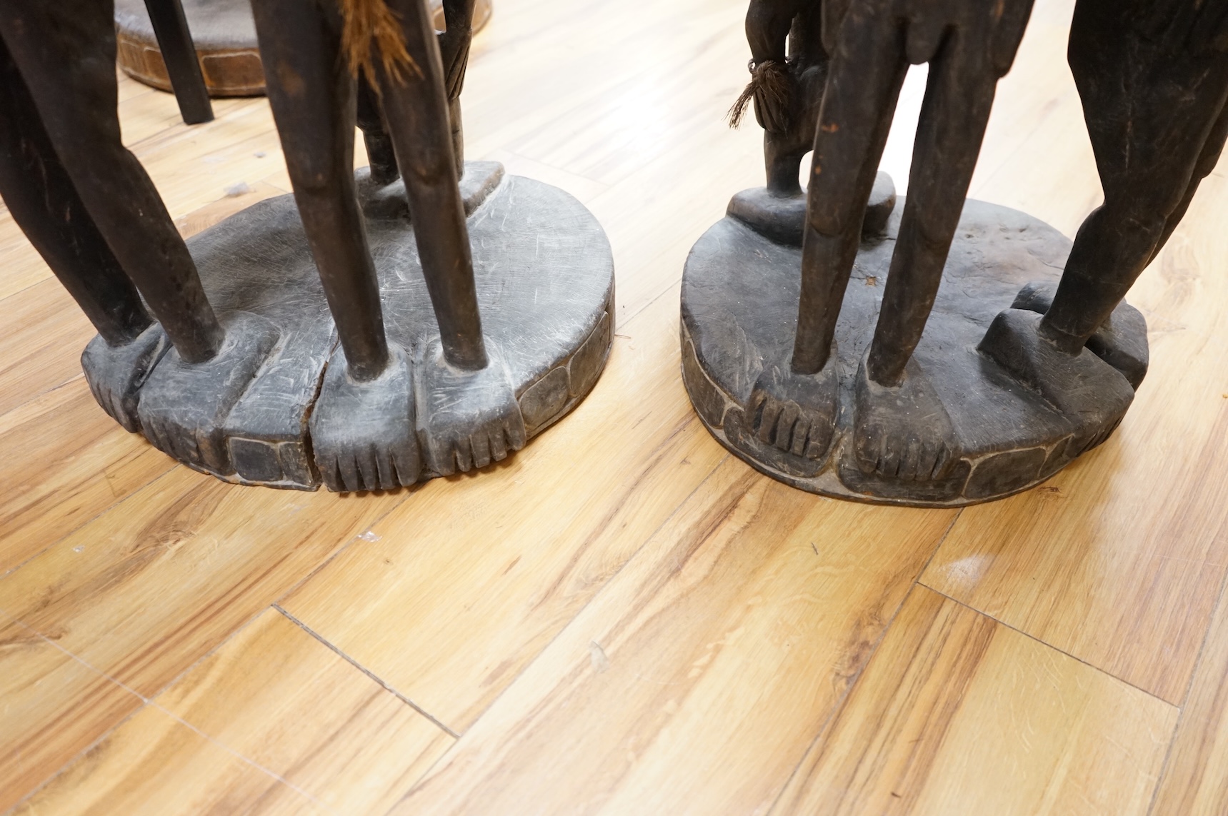 Papua New Guinea Sepik River, a near pair of ‘ceremonial’ figural chairs, each carved from a single section of a tree trunk with integral male and female backs and an castor figure front support with cowrie shell eyes. H